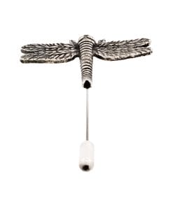 Close-up of a metal dragonfly sculpture with ribbed body and patterned wings mounted on a vertical rod against a white background.