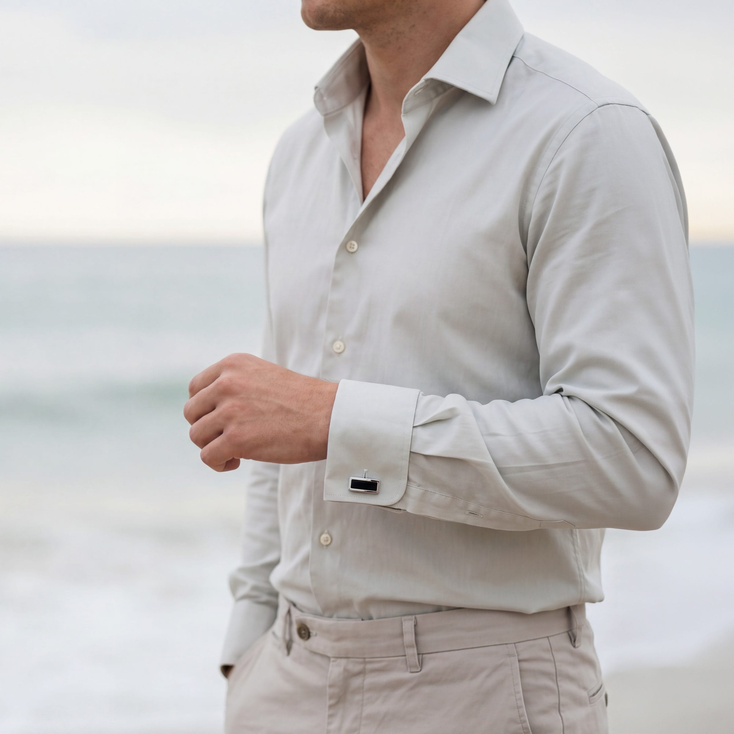 227-05BM | Cudworth Man wearing a light beige button-down shirt standing at the beach, torso visible from chest to hips